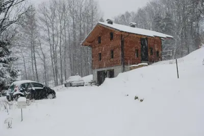 a barn covered in snow with a car parked next to it at Appartement 25m2 à Saint-Gervais les bains in Saint-Gervais-les-Bains