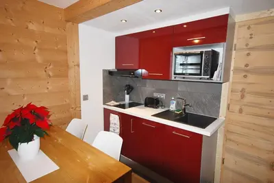 a kitchen with red cabinets and a wooden table at Appartement 25m2 à Saint-Gervais les bains in Saint-Gervais-les-Bains