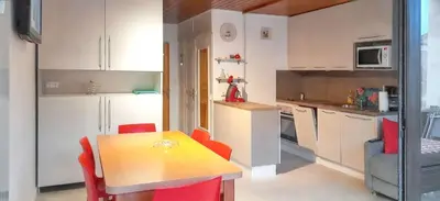 a kitchen with a table and red chairs in a room at Studio accueillant à Les Carroz, 27 m², vue montagne in Les Carroz d'Araches