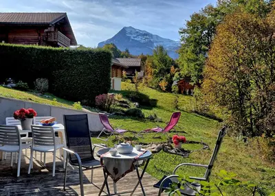a patio with a table and chairs and a mountain at Appartement cosy aux Carroz, 40 m², vue sur la montagne in Les Carroz d'Araches