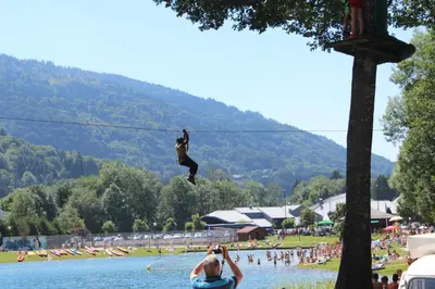 a person on a zip line over a body of water at Village De Vacances Les Flocons Verts in Les Carroz d'Araches