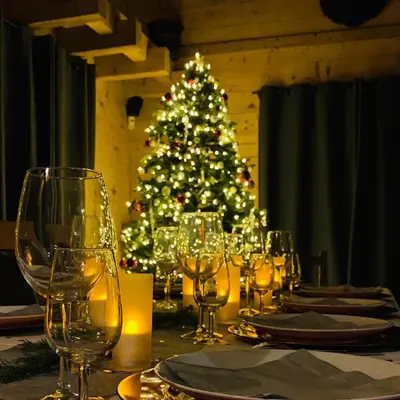 a table with wine glasses and a christmas tree at Chalet Krystal in Arâches-la-Frasse