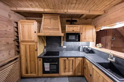 a kitchen with wooden cabinets and a stove at Chalet Krystal in Arâches-la-Frasse