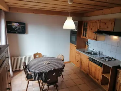 a kitchen with a table with chairs and a sink at Résidence Chalet des Granges in Samoëns