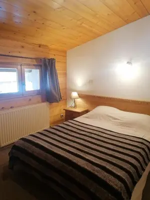 a bedroom with a large bed in a wooden room at Résidence Chalet des Granges in Samoëns
