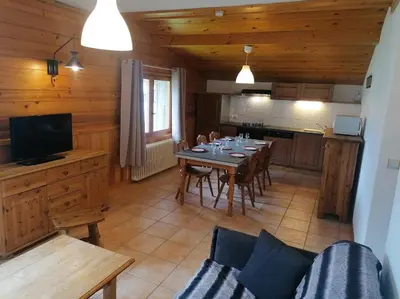 a living room with a dining room table and a kitchen at Résidence Chalet des Granges in Samoëns