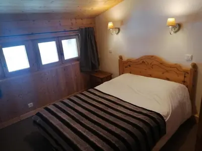 a bedroom with a bed and two windows at Résidence Chalet des Granges in Samoëns
