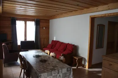 a living room with a red couch and a table at Résidence Chalet des Granges in Samoëns