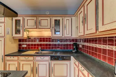 a kitchen with white cabinets and red tiles at APARTMENT PRESIDENT - Alpes Travel - Central Chamonix - Sleeps 12 in Chamonix-Mont-Blanc
