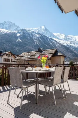 a table and chairs on a deck with mountains at APARTMENT PRESIDENT - Alpes Travel - Central Chamonix - Sleeps 12 in Chamonix-Mont-Blanc