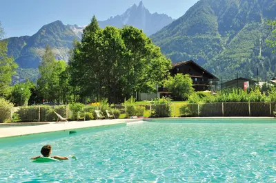 a person swimming in a pool with mountains in the background at VTF Les Econtres in Chamonix-Mont-Blanc