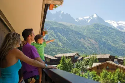 a family standing on a balcony looking out at the mountains at VTF Les Econtres in Chamonix-Mont-Blanc
