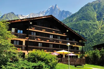 a large building with mountains in the background at VTF Les Econtres in Chamonix-Mont-Blanc