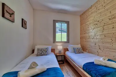 two twin beds in a room with a window at Base Camp: Residence Ferme de Montenvers in Chamonix-Mont-Blanc