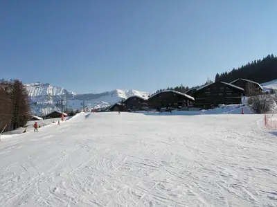 a snow covered ski slope with a ski lodge at Appartement Hameau des Pistes - Ski-in and Ski-out in Megève