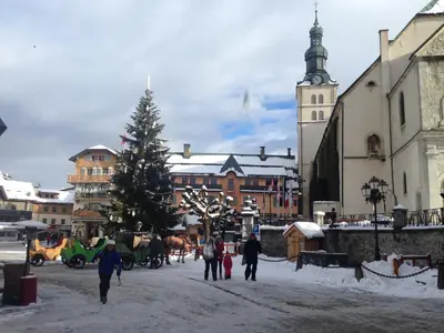a group of people walking down a street with a christmas tree at Appartement Hameau des Pistes - Ski-in and Ski-out in Megève