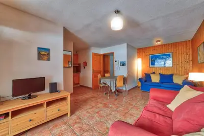 a living room with a blue couch and a tv at Carabiner: Residence Espace Montagne in Chamonix-Mont-Blanc