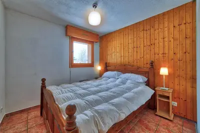 a large bed in a room with a wooden wall at Carabiner: Residence Espace Montagne in Chamonix-Mont-Blanc