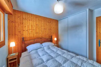a bedroom with a large bed with a wooden wall at Carabiner: Residence Espace Montagne in Chamonix-Mont-Blanc