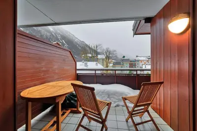 a balcony with a wooden table and two chairs at Carabiner: Residence Espace Montagne in Chamonix-Mont-Blanc