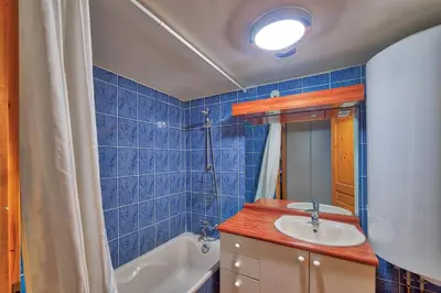 a blue tiled bathroom with a sink and a tub at Carabiner: Residence Espace Montagne in Chamonix-Mont-Blanc