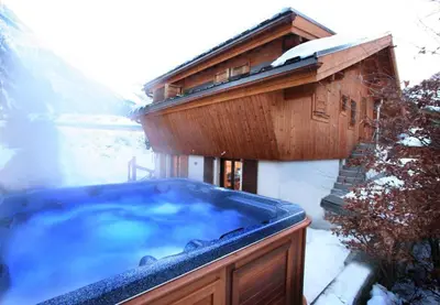 a hot tub in front of a house in the snow at Chalet Grand Cru in Chamonix-Mont-Blanc