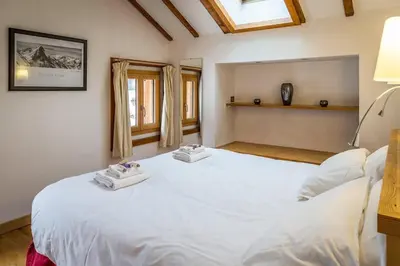 a bedroom with a large white bed with two towels on it at Chalet Grand Cru in Chamonix-Mont-Blanc