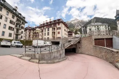 a group of buildings with cars parked in a parking lot at Paccard: Residence Le Lutetia in Chamonix-Mont-Blanc