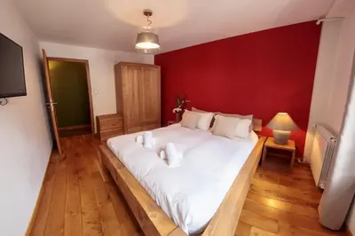 a large bed in a room with a red wall at Paccard: Residence Le Lutetia in Chamonix-Mont-Blanc
