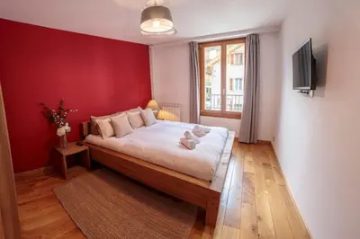 a bedroom with a large bed with a red wall at Paccard: Residence Le Lutetia in Chamonix-Mont-Blanc