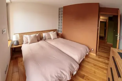 a large white bed in a room with wooden floors at Paccard: Residence Le Lutetia in Chamonix-Mont-Blanc