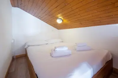 a bedroom with a white bed with a wooden ceiling at Skyhook: Batiment B in Chamonix-Mont-Blanc
