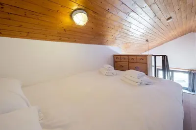 a bedroom with a white bed with a wooden ceiling at Skyhook: Batiment B in Chamonix-Mont-Blanc