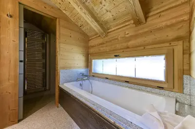 a bath tub in a wooden bathroom with a window at Chalet Noemie in Les Houches