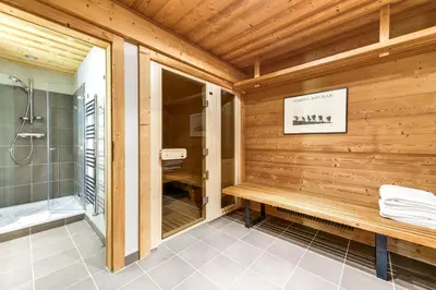a wooden bathroom with a shower and a bench at Chalet Noemie in Les Houches