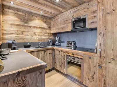 a kitchen with wooden cabinets and a stove top oven at Superbe duplex à Megève pour 7 pers., parking - FR-1-453-25 in Megève