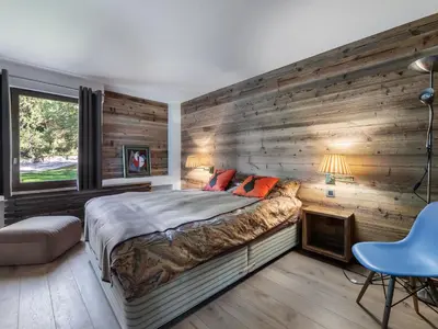 a bedroom with a wooden wall with a bed at Appartement duplex 2 ch., terrasse, proche pistes à Megève - FR-1-453-26 in Megève
