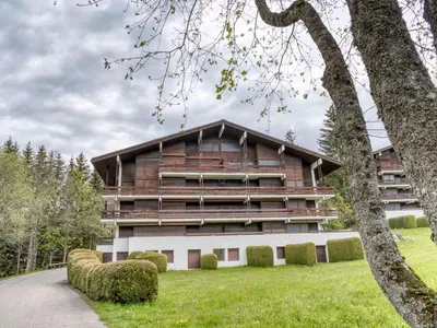 an exterior view of a building with a green yard at Appartement duplex 2 ch., terrasse, proche pistes à Megève - FR-1-453-26 in Megève