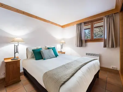 a bedroom with a large white bed with blue pillows at Duplex 3 Chambres à Megève - Confort et Wifi - FR-1-453-49 in Megève