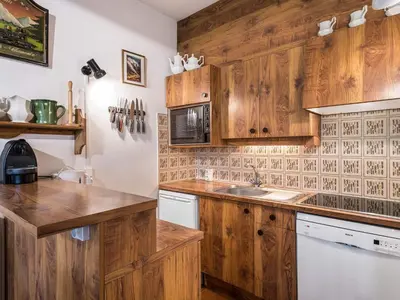 a kitchen with wooden cabinets and a sink at Appartement cosy 2 chambres, terrasse et parking à Megève - FR-1-453-52 in Megève