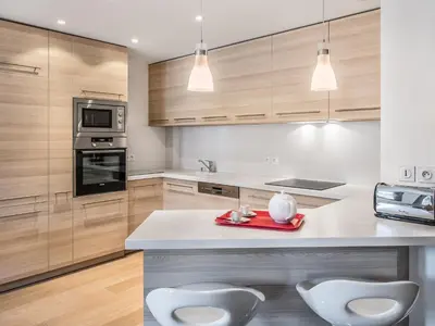 a kitchen with wooden cabinets and a counter with two white chairs at Appartement central 2 chambres avec balcon et Wifi à Megève - FR-1-453-53 in Megève
