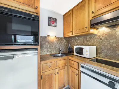 a kitchen with wooden cabinets and a microwave and a sink at Appartement cosy 1 chambre à Megève, animaux admis - FR-1-453-63 in Megève