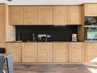 a kitchen with wooden cabinets and a black wall at Appartement rénové 2 chambres à Megève Centre avec balcon - FR-1-453-66 in Megève