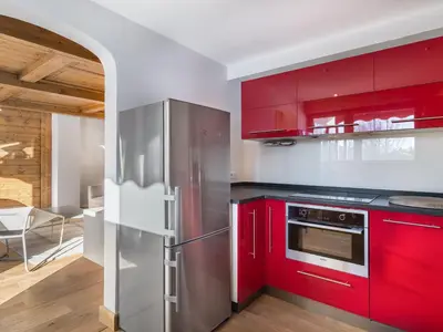 a kitchen with red cabinets and a stainless steel refrigerator at Spacieux T2 rénové avec Parking et WiFi à Megève, Proche Pistes - FR-1-453-68 in Megève