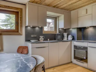 a kitchen with white cabinets and a table at Charmant 2 pièces proche pistes à Megève - FR-1-453-83 in Megève