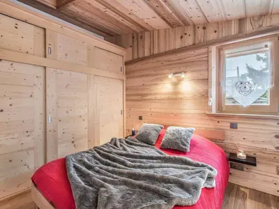 a bedroom with a red bed in a wooden room at Charmant 3 pièces au centre de Megève, idéal 4 pers - FR-1-453-96 in Megève