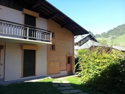 a building with a balcony and a door and a yard at Charmant 3 pièces au centre de Megève, idéal 4 pers - FR-1-453-96 in Megève