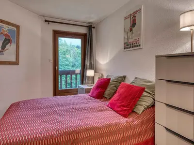 a bedroom with a bed with red pillows and a window at Appartement 2 Chambres Megève, Balcon Sud, Parking, Wifi - FR-1-453-101 in Megève