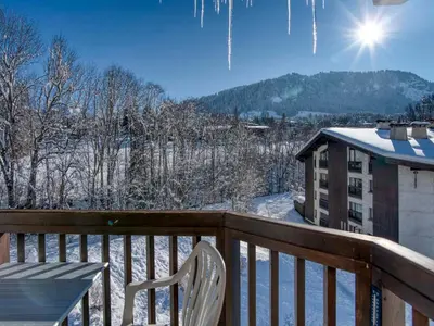 a table and a chair on a balcony with snow at Appartement 2 Chambres Megève, Balcon Sud, Parking, Wifi - FR-1-453-101 in Megève
