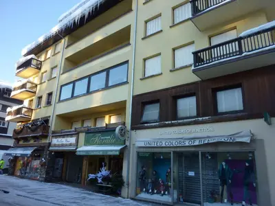 a tall yellow building with shops on a street at Appartement 2 chambres en centre-ville à Megève avec balcon et wifi - FR-1-453-107 in Megève